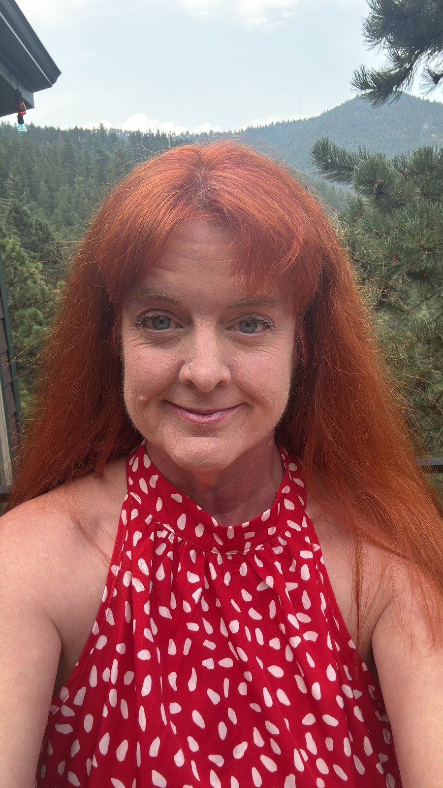Annette Thompson, who publishes Outdoor Boulder, photographed at home in the Boulder foothills with forested hillside behind her.